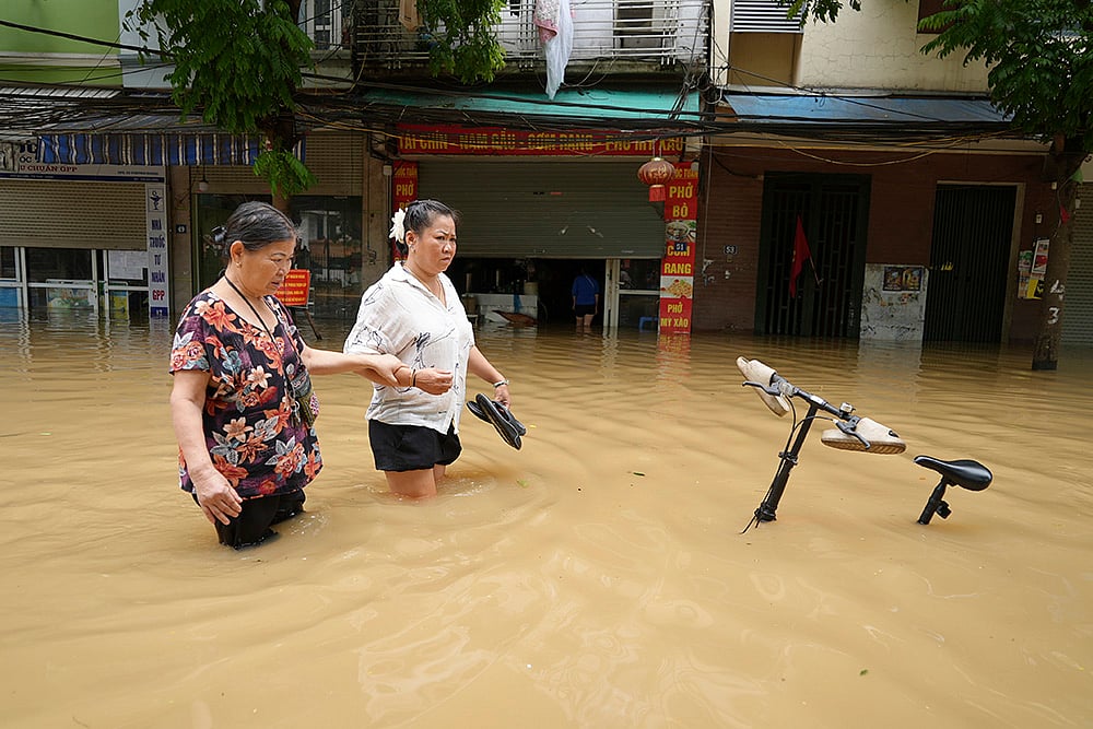People wade in a flooded street in Hanoi - | Photo: AP/Hau Dinh